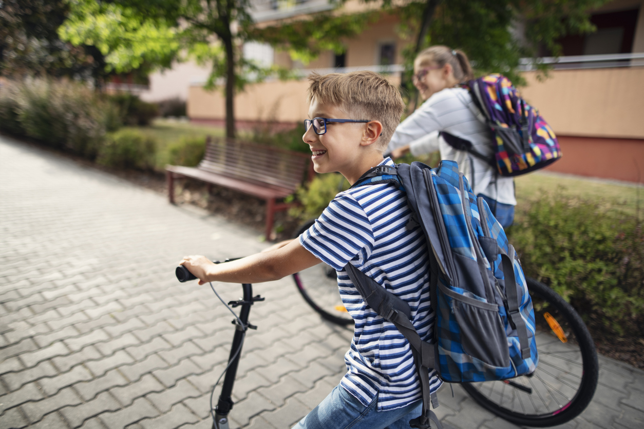 Kinderen op de fiets en step met een schooltas